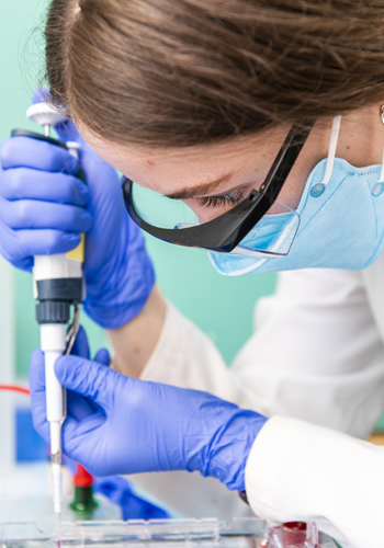 A woman is working in a lab with a pipette.